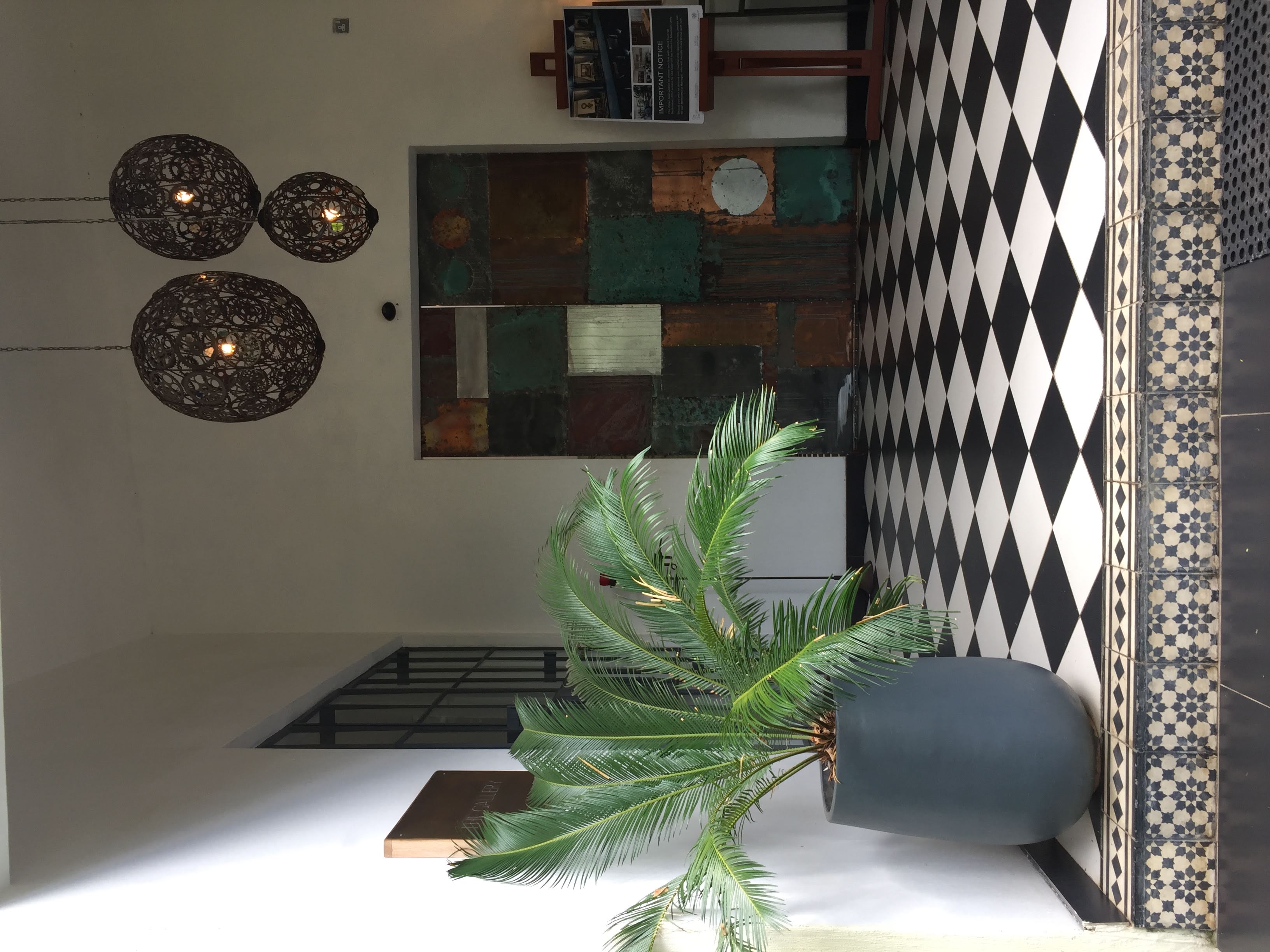 Ornate patinated metal door in the entrance hall, ornamental pendant lanterns, and bold tilework