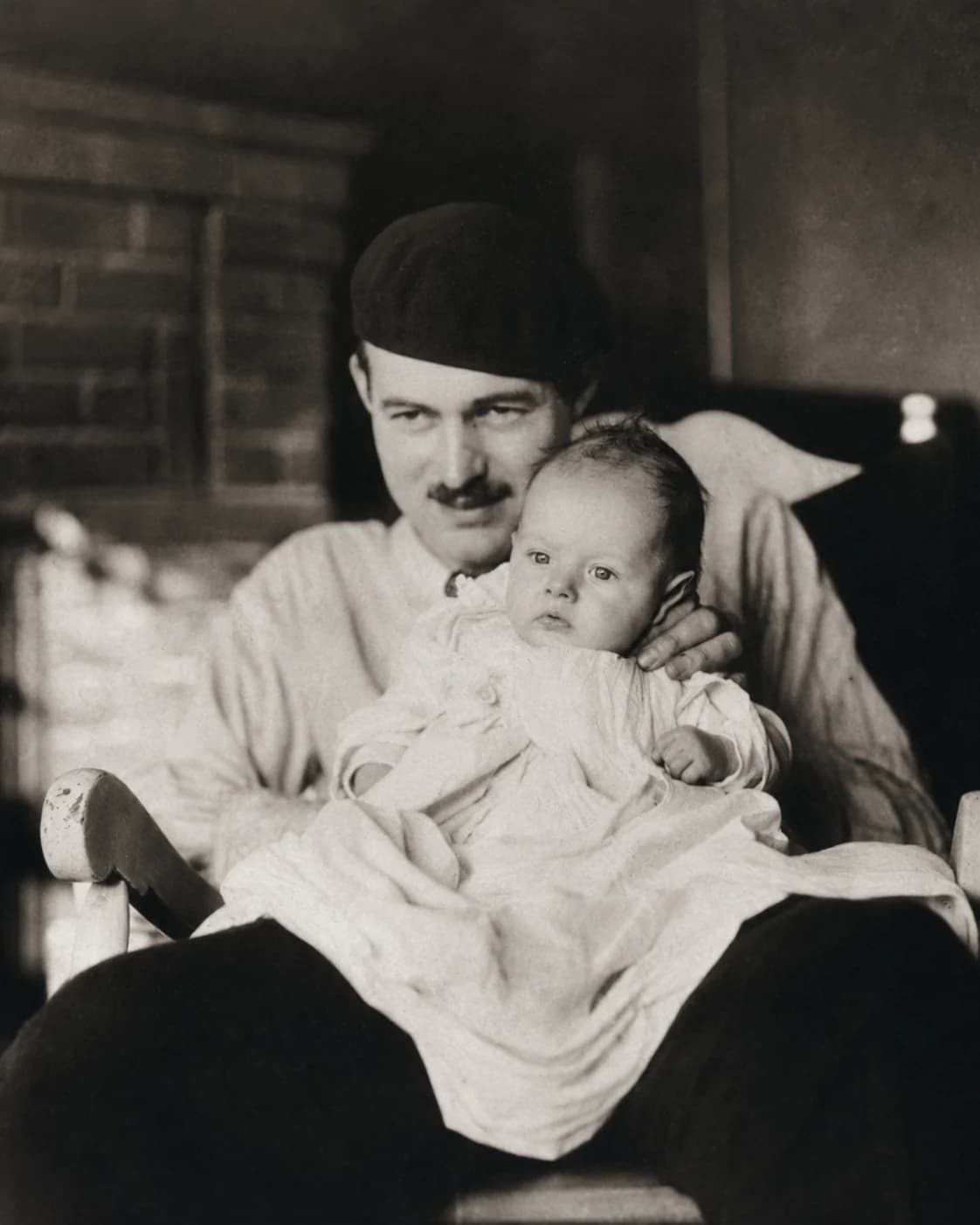 Black-and-white editorial portrait of Ernest Hemingway holding his infant son in Paris