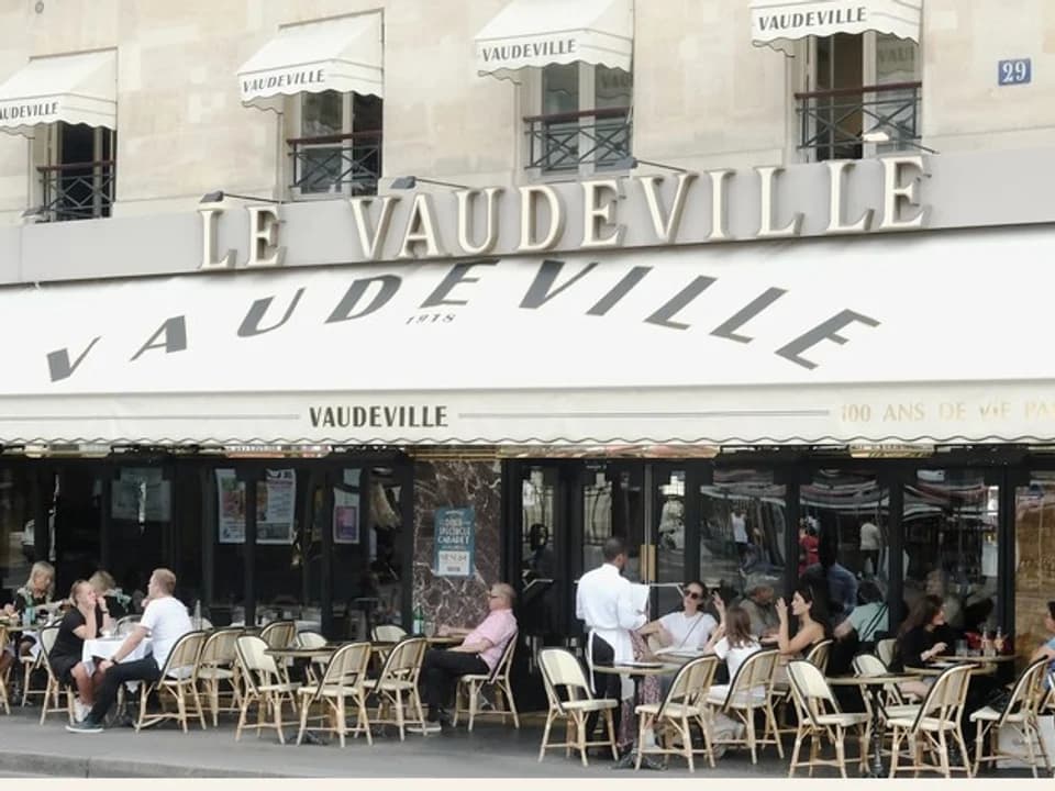 The white Vaudeville brasserie facade and sidewalk terrace in Paris
