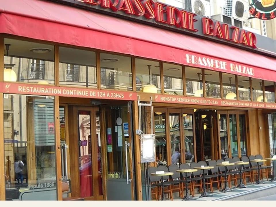The red awning and street-facing windows of Brasserie Balzar in Paris