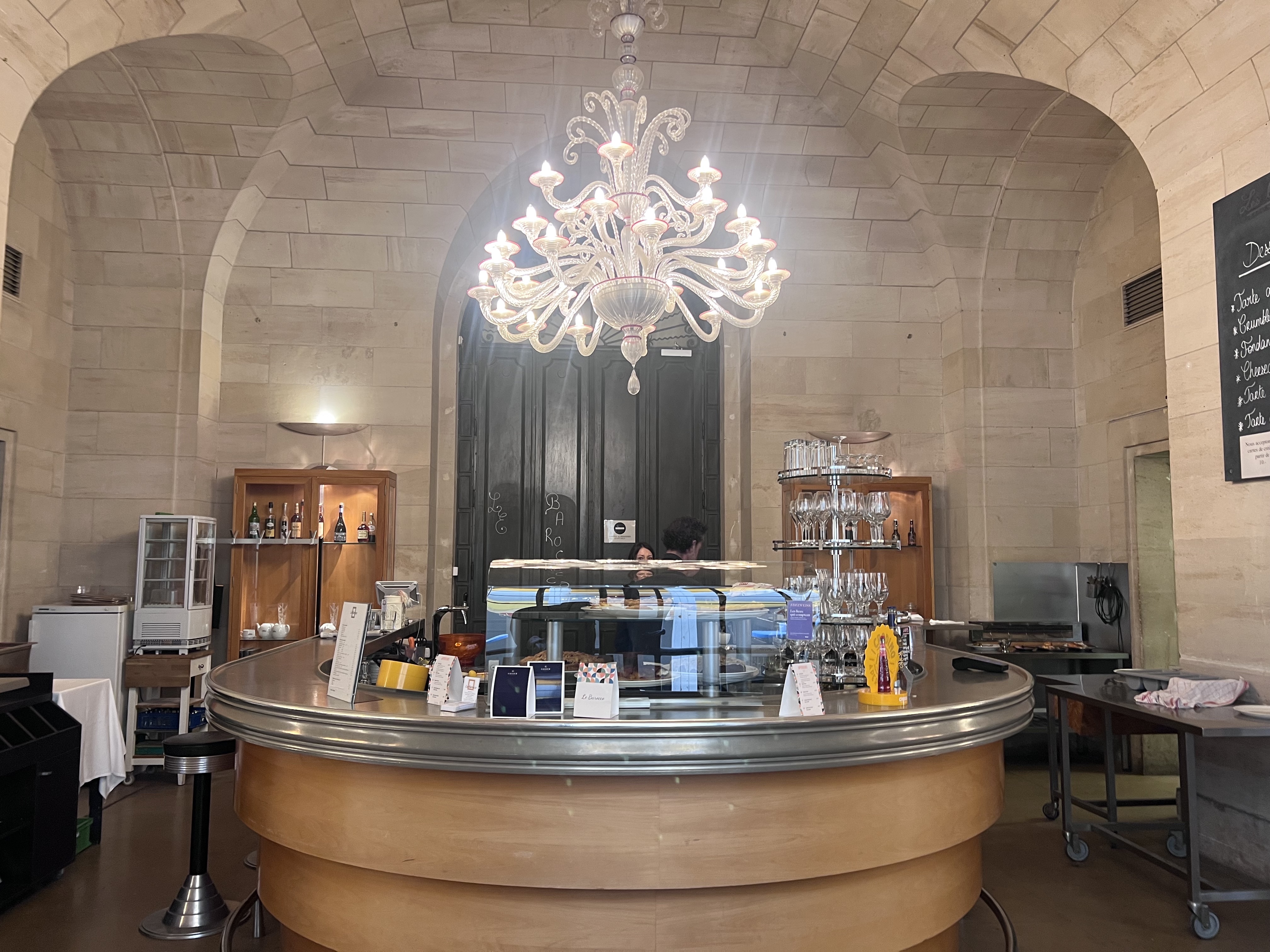Café in the basement of Musée d'Art et d'Histoire Geneva — chandelier, circular bar, stone arches