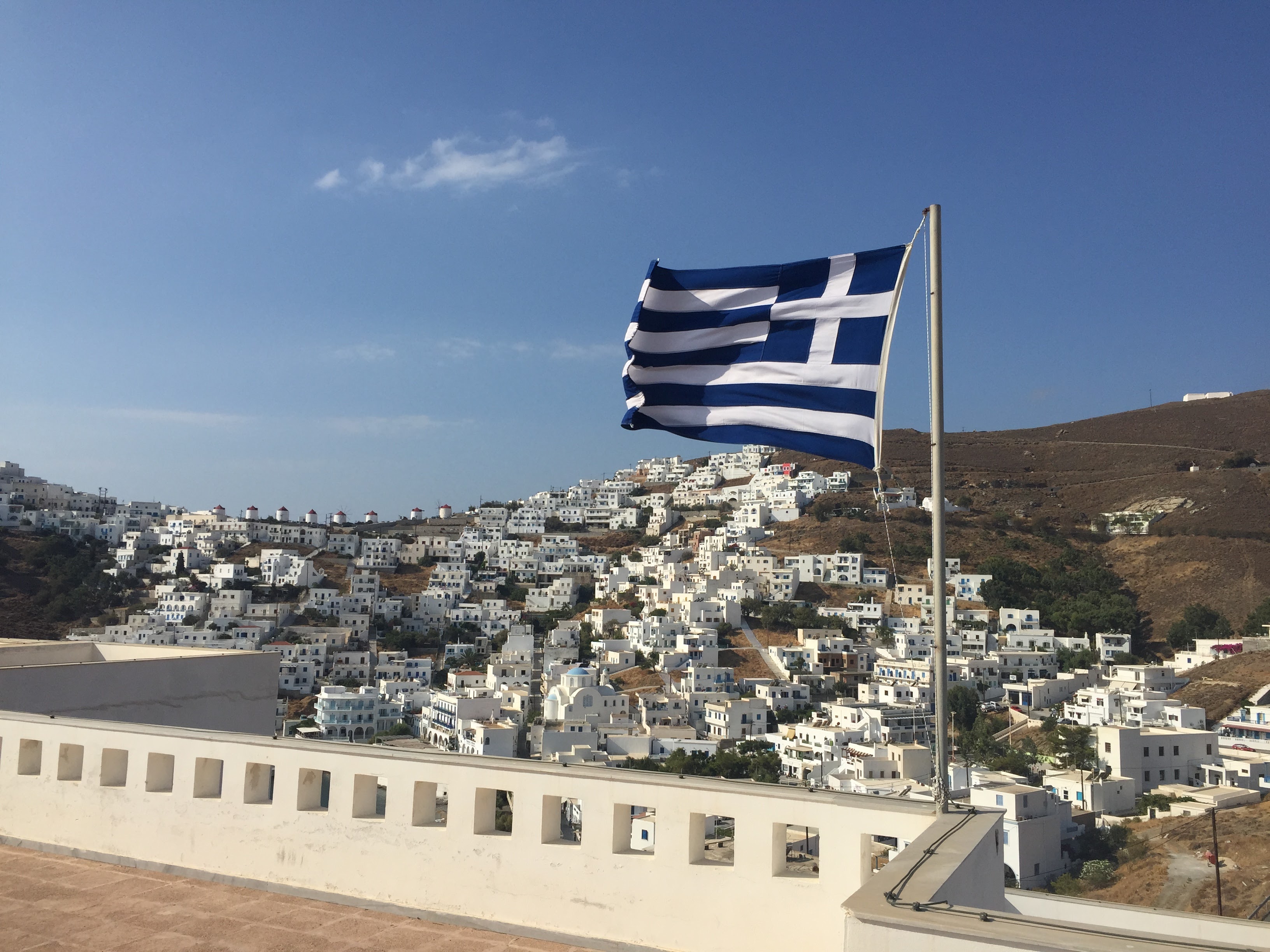 Greek flag and the white village of Astypalea Chora on the hillside