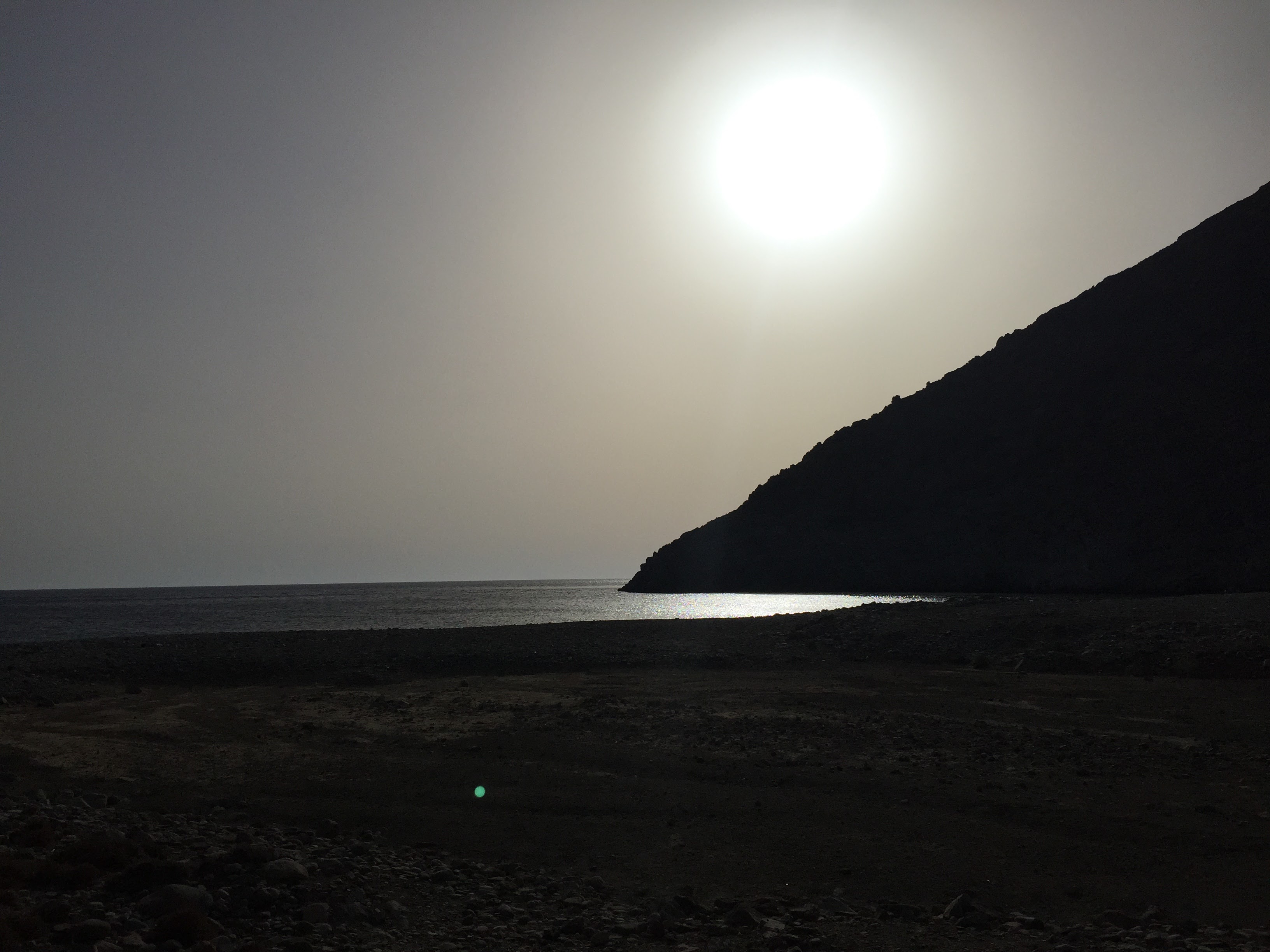 Dramatic sunset silhouette over a remote beach in Astypalea
