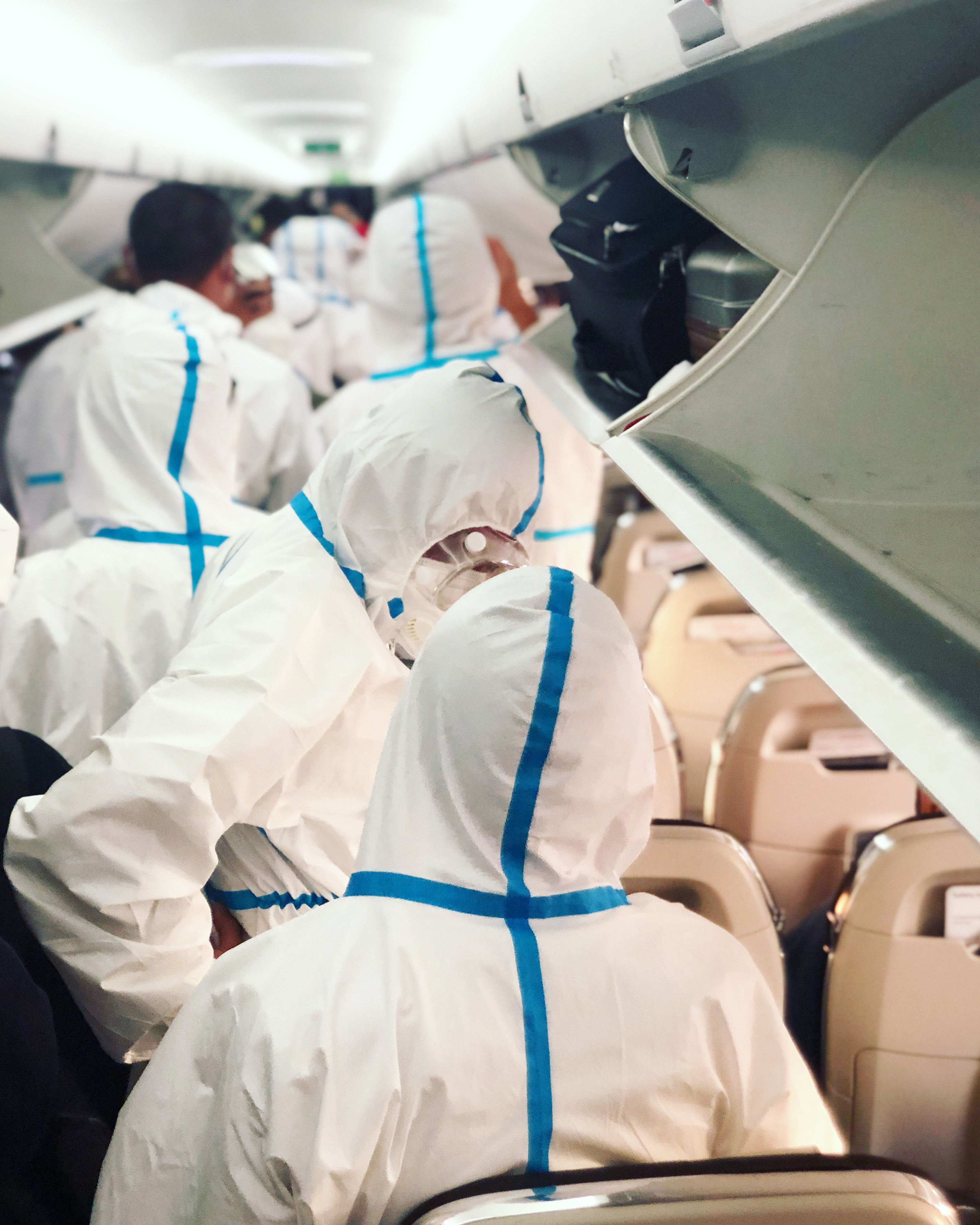 A plane full of passengers in full hazmat suits — context for the era