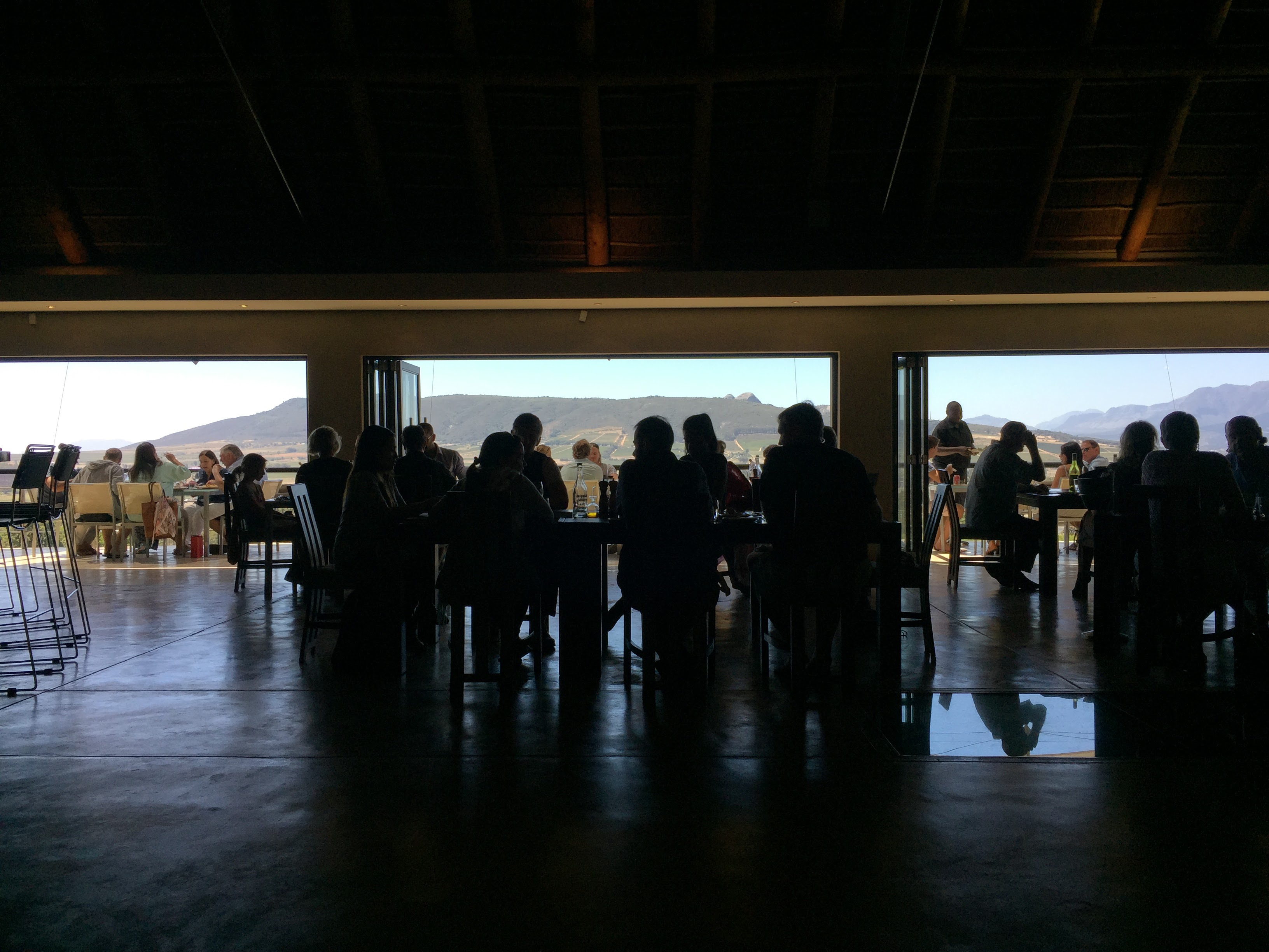 Glen Carlou tasting room — silhouettes of diners against the mountain view, full lunch service
