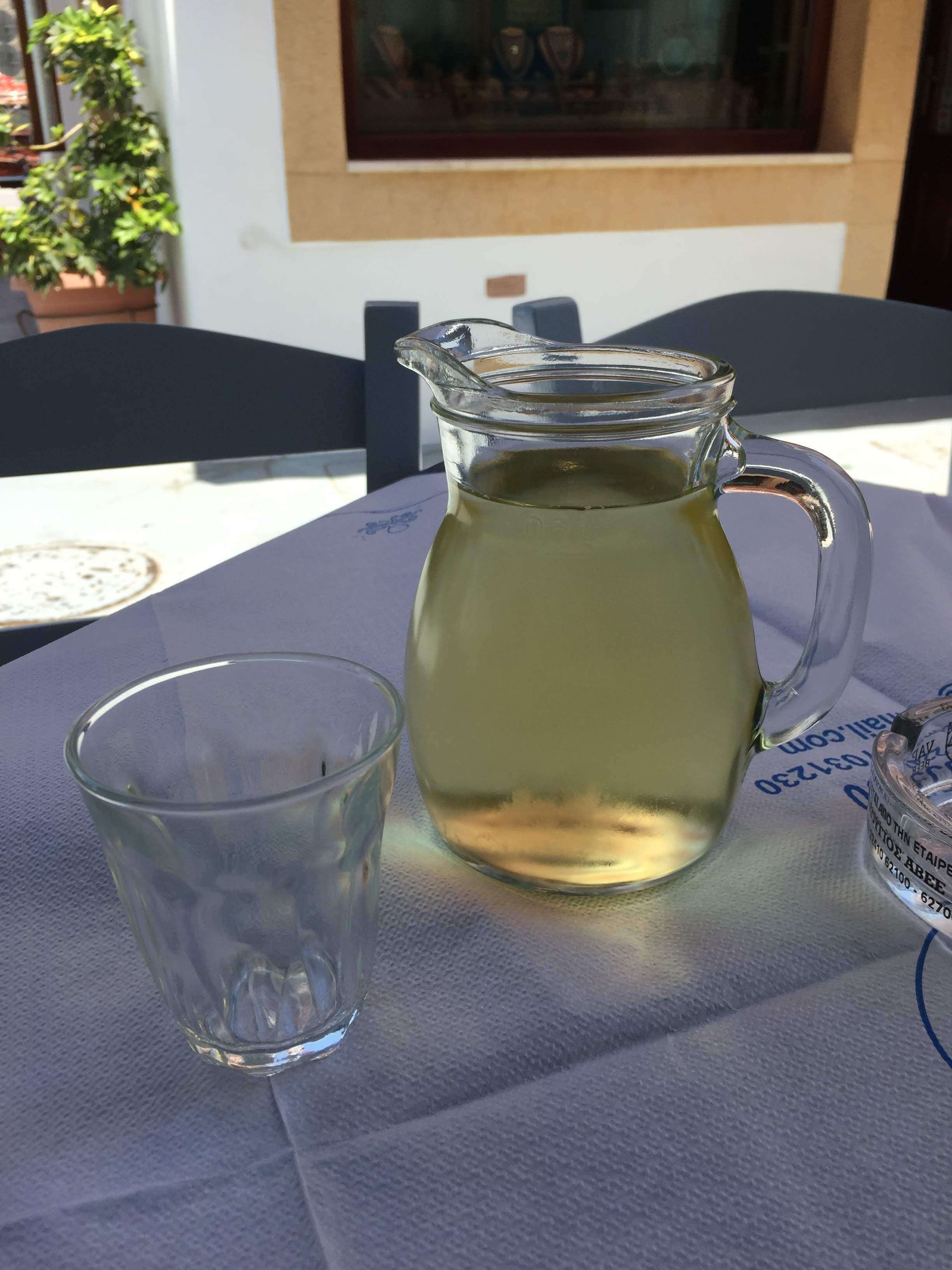 A glass jug of cold Greek house white wine on a taverna table