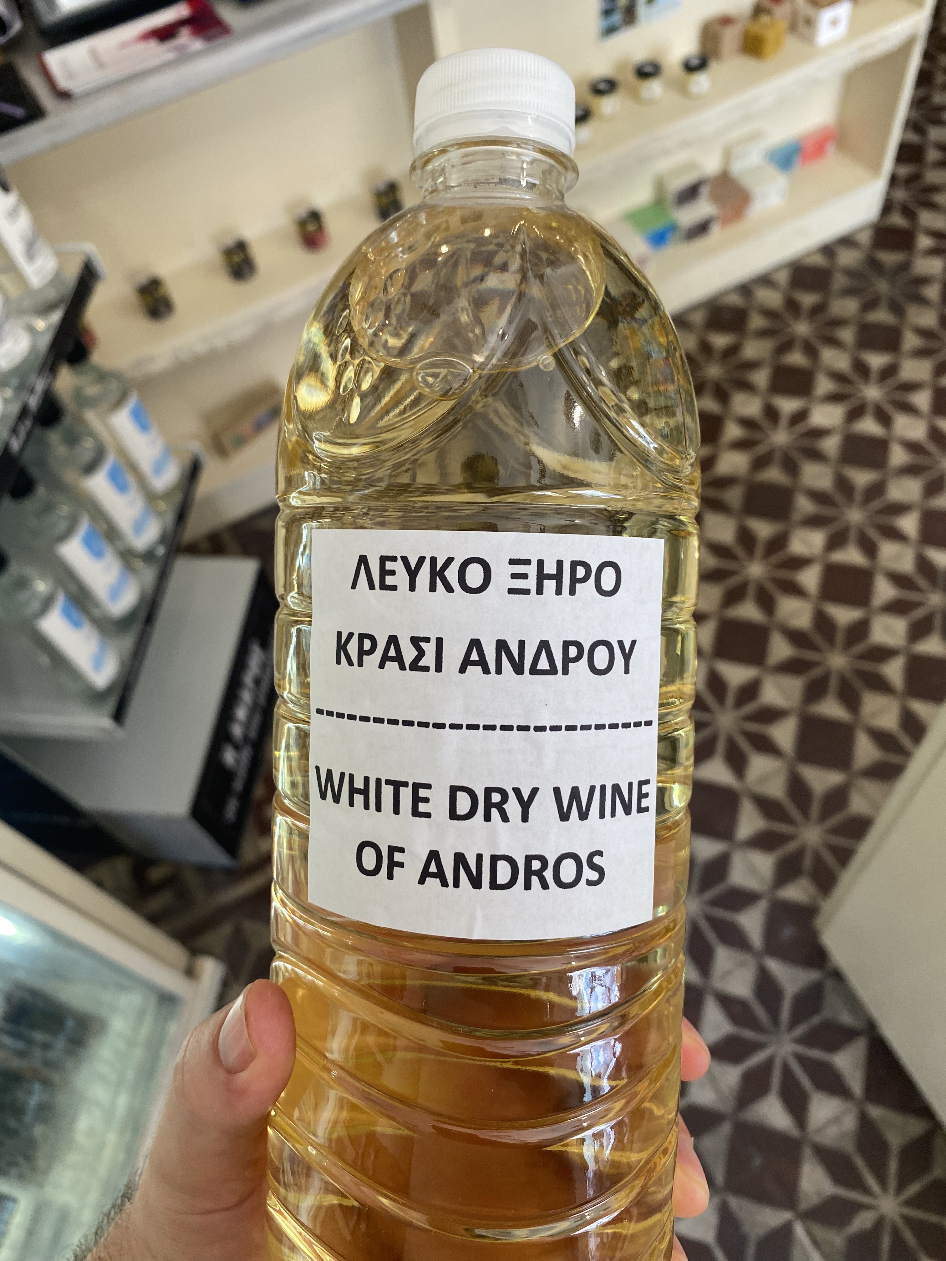 A 1.5L plastic bottle of cold local wine labelled in Greek and English: White Dry Wine of Andros