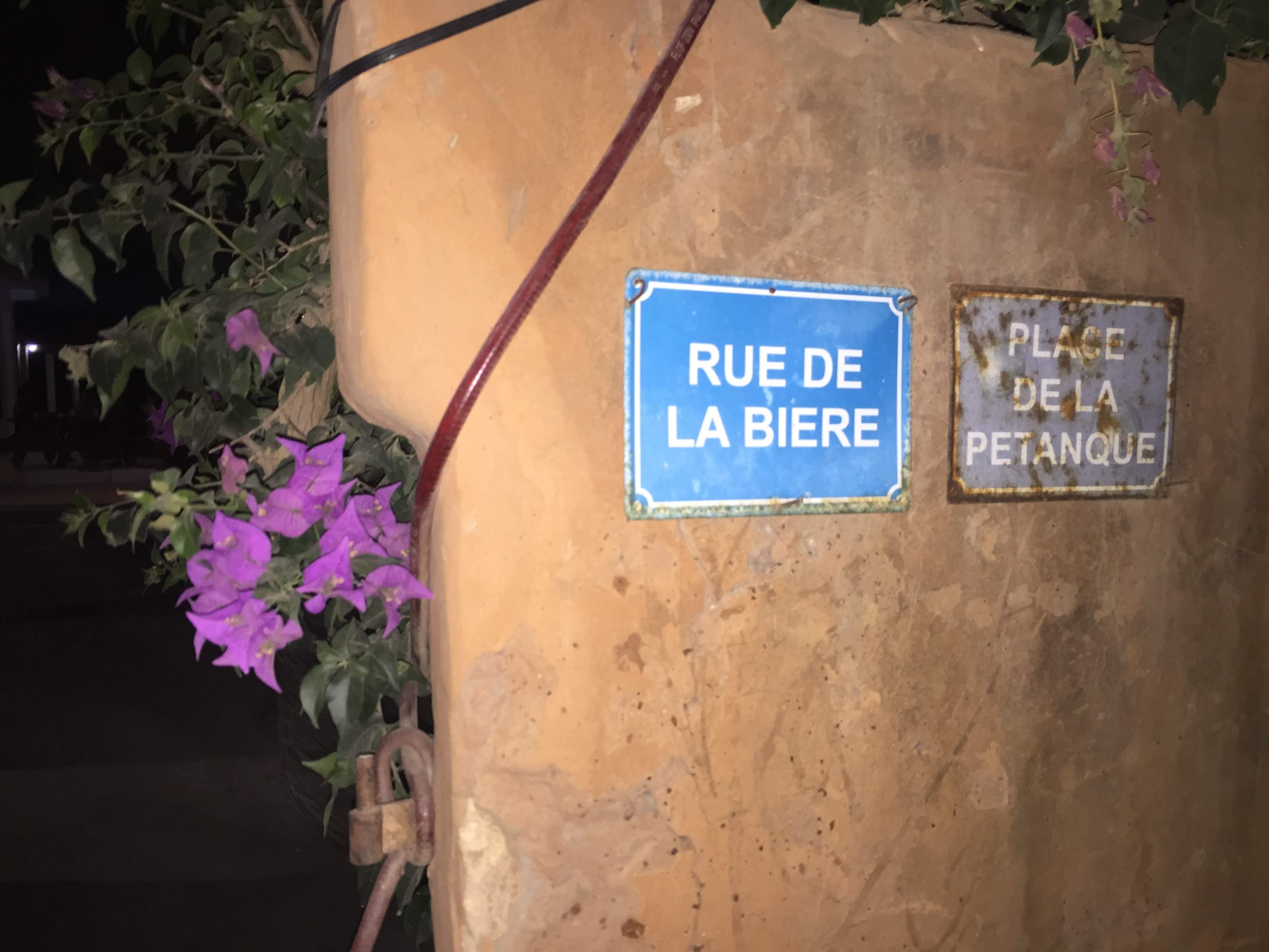 Rue de la Bière / Place de la Pétanque sign — Le Balafon entrance, Popenguine at night