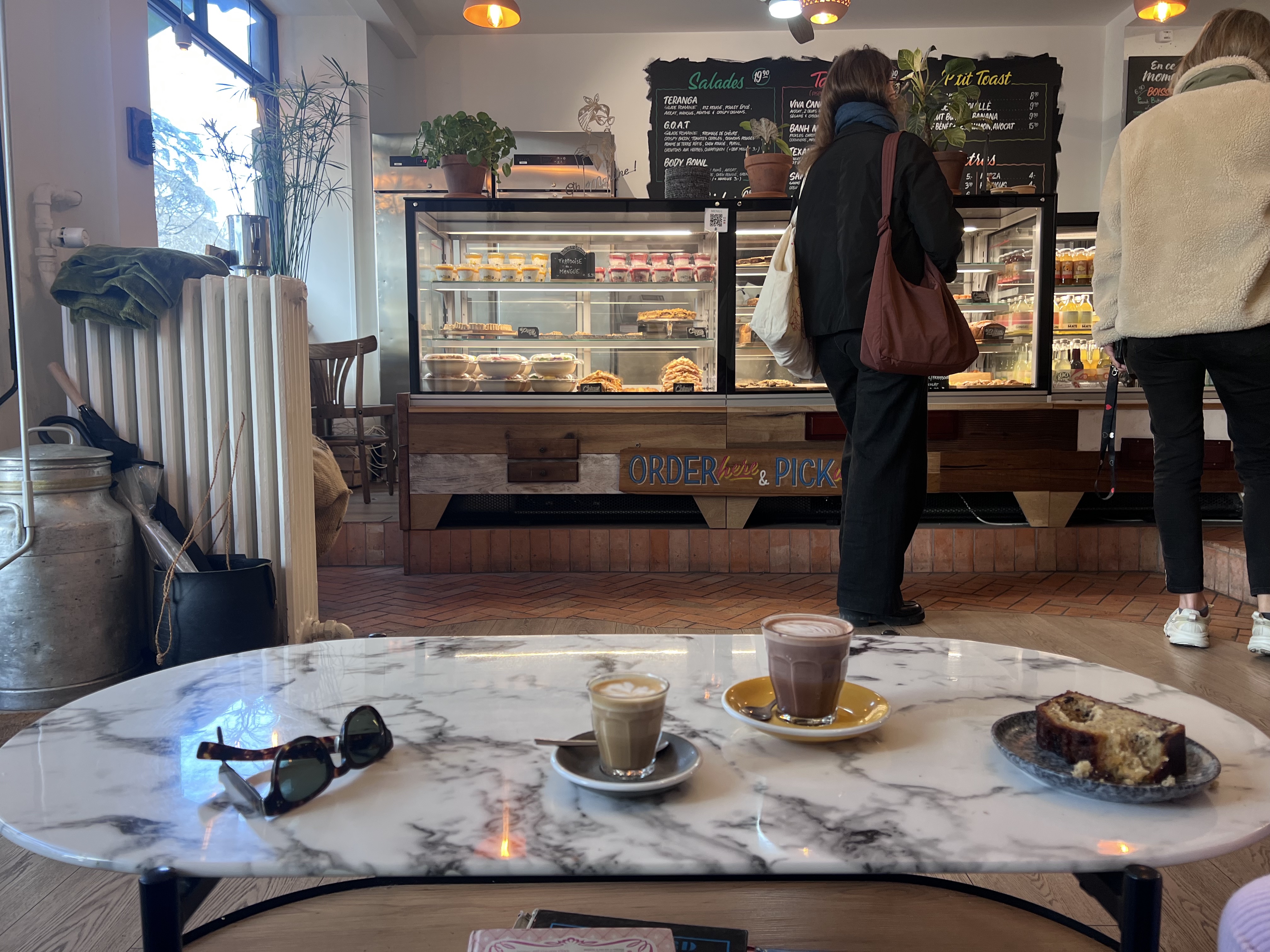 Oh Martine! Eaux-Vives interior — marble table, cortado and hot chocolate, counter with pastries