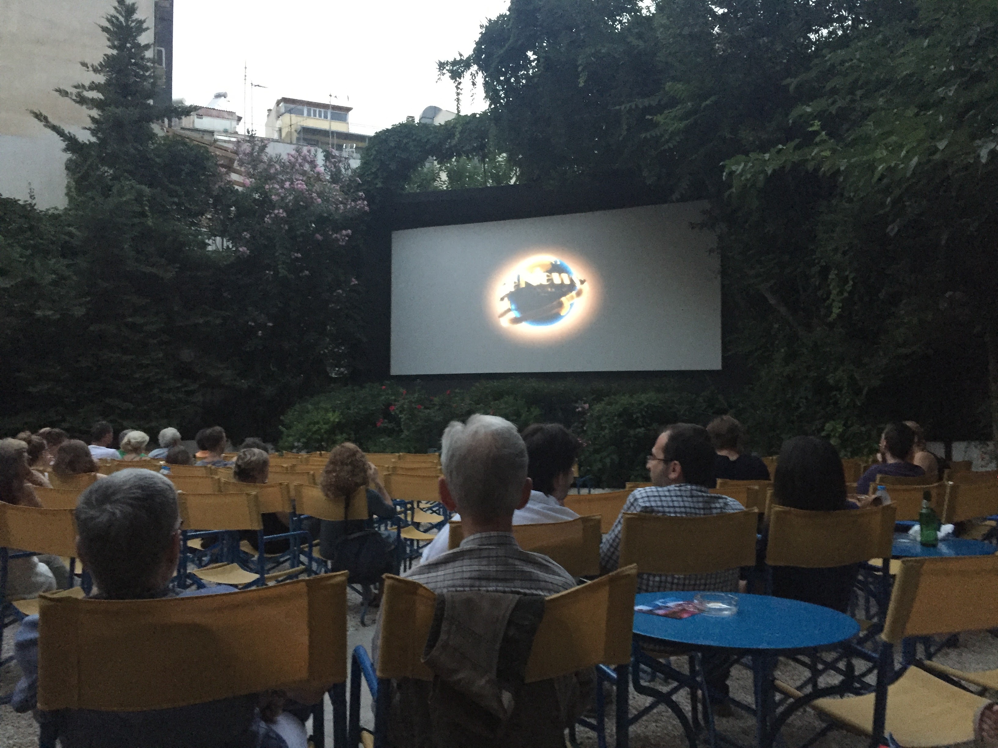 Cinema Riviera at night — audience, wooden chairs, Universal logo on screen, Exarchia Athens