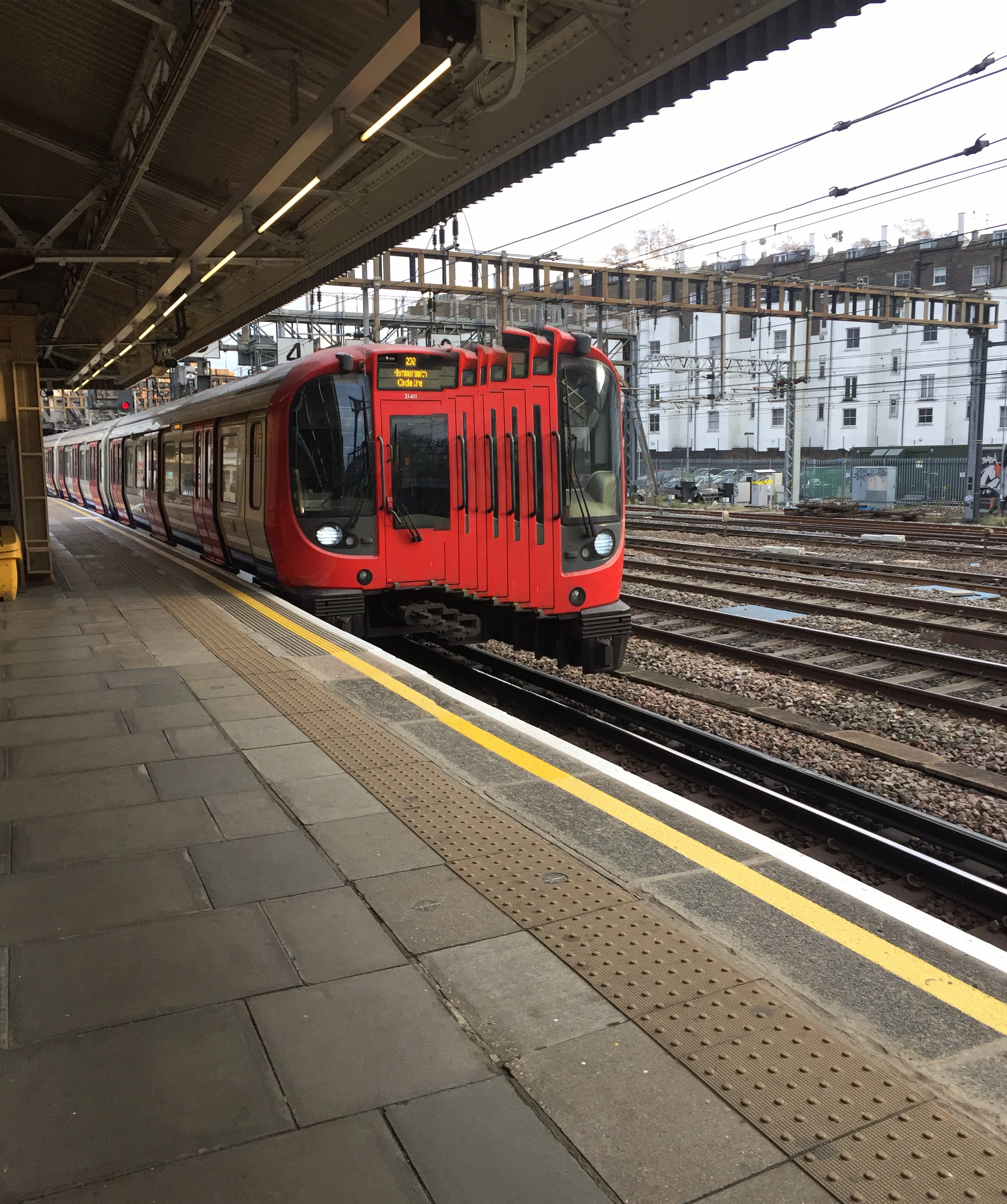 Red Circle line train arriving at station, panorama distortion