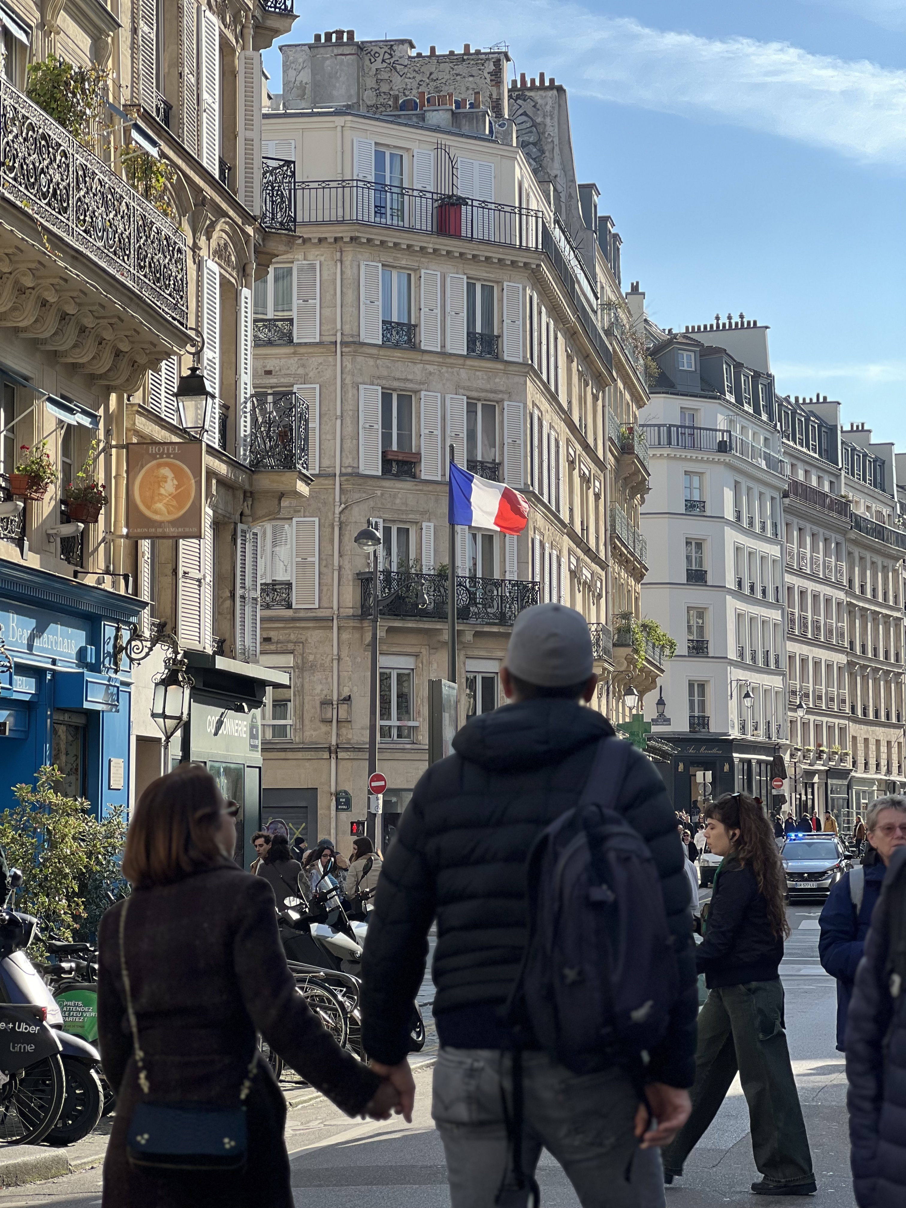 Paris street scene — couple walking, French flag, Haussmann buildings
