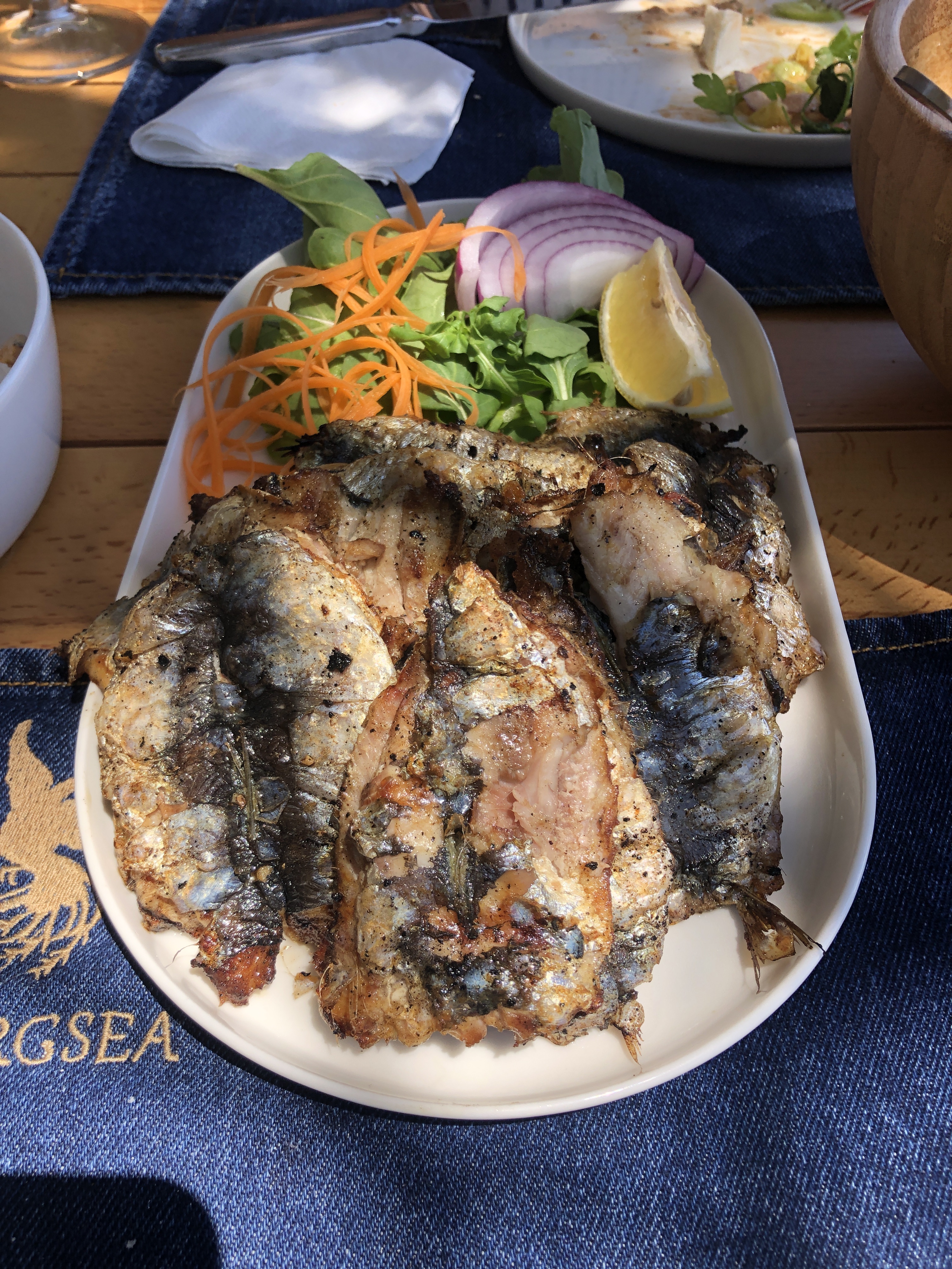 A plate of grilled sardines with carrot, rocket, red onion and lemon at Simurg Sea