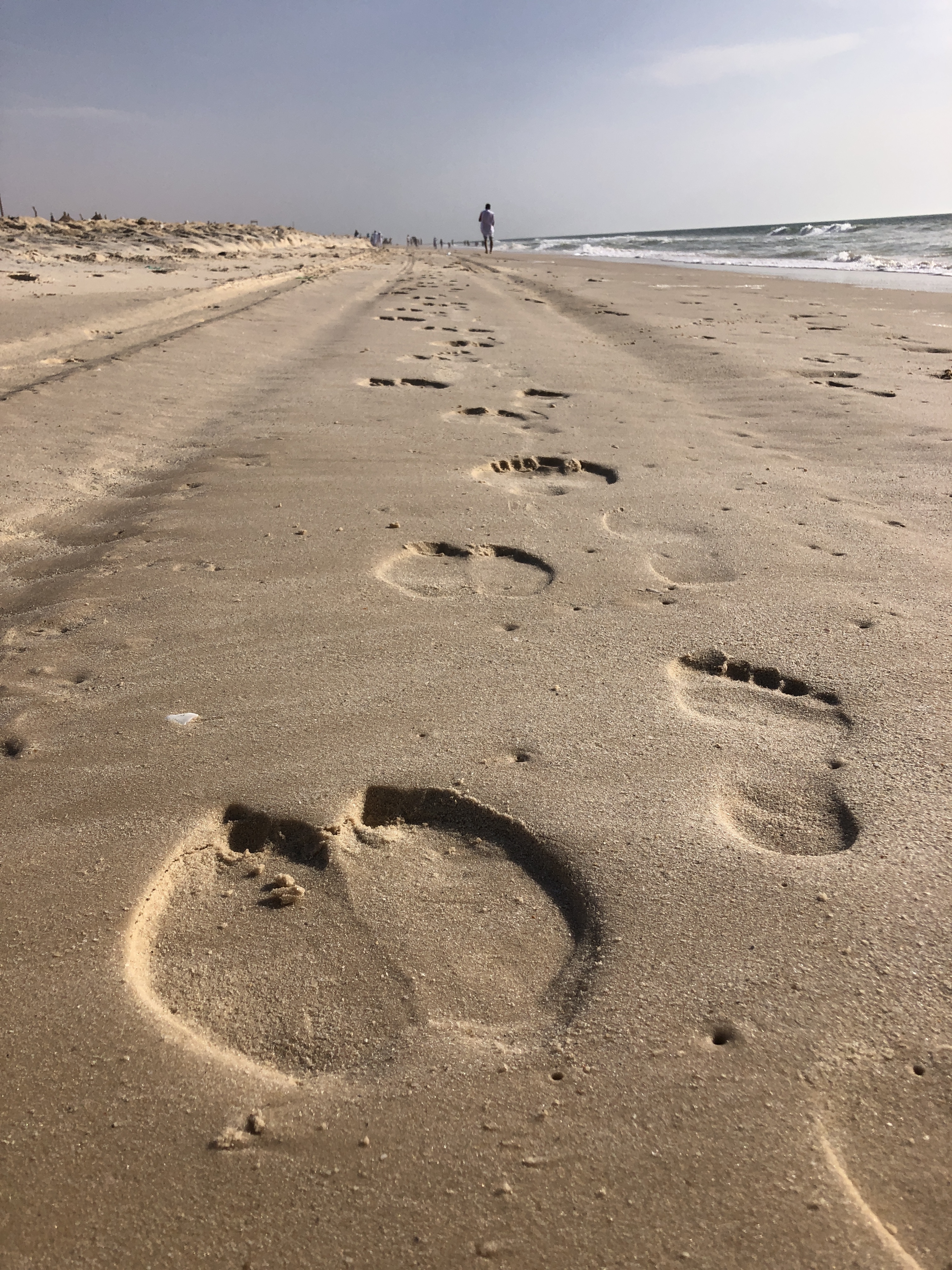 Footprints in the sand on the long empty beach at Nouakchott, lone figure walking in the distance