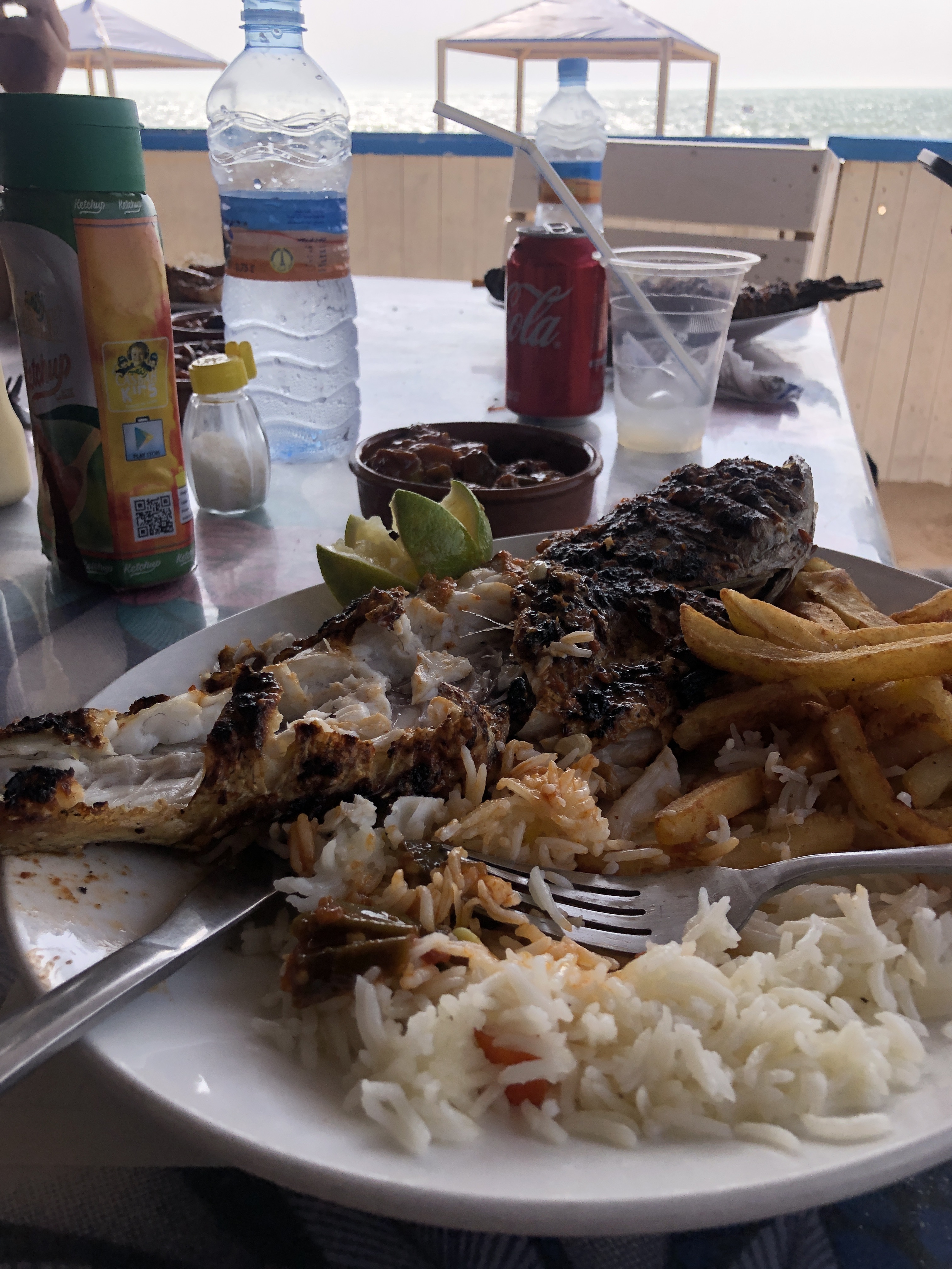 Grilled fish with rice and chips at Le Soultane, the ocean visible through the beach shack behind