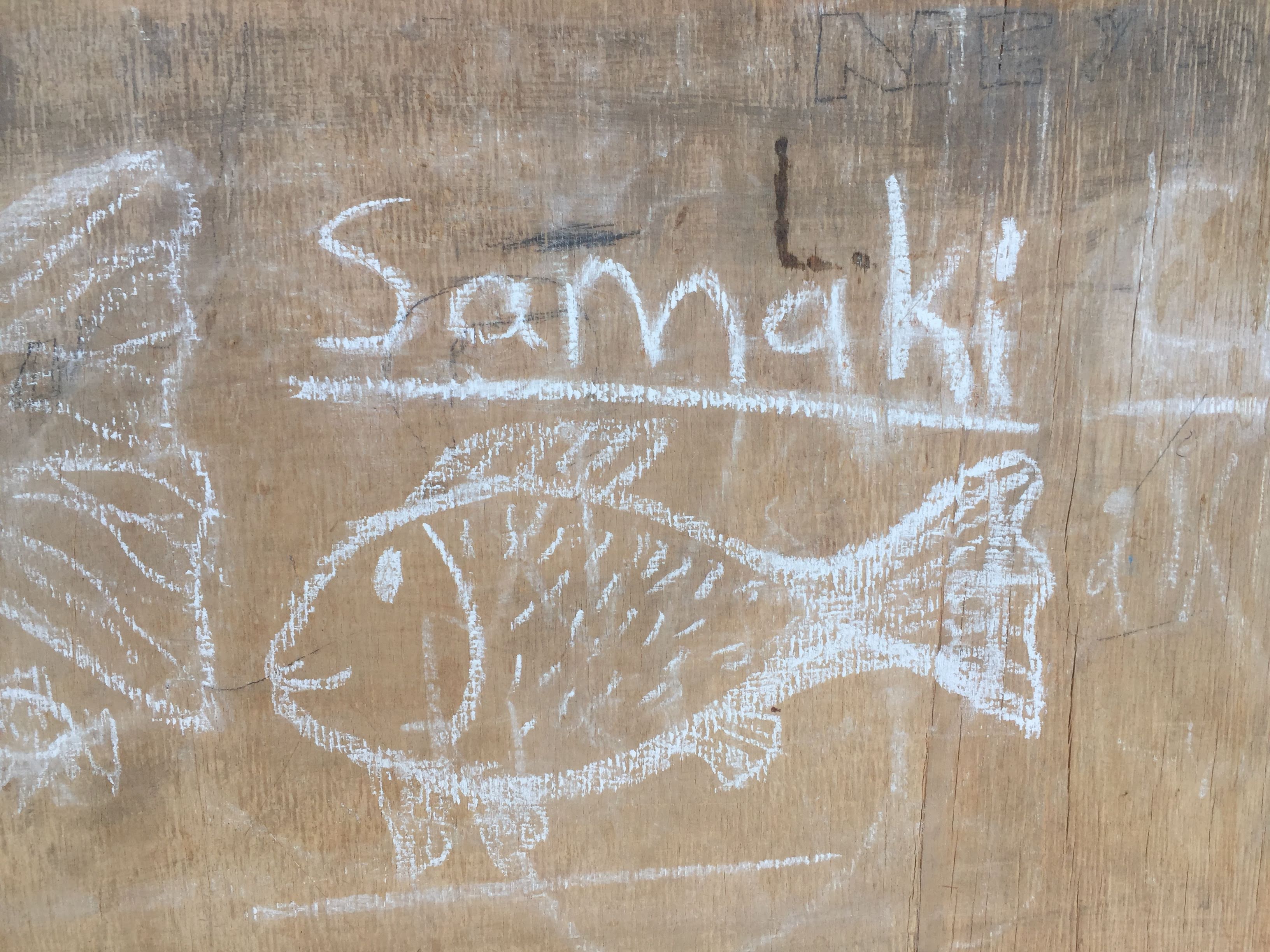Chalk drawing of a fish on wood with the word 'Samaki' — fish in Swahili