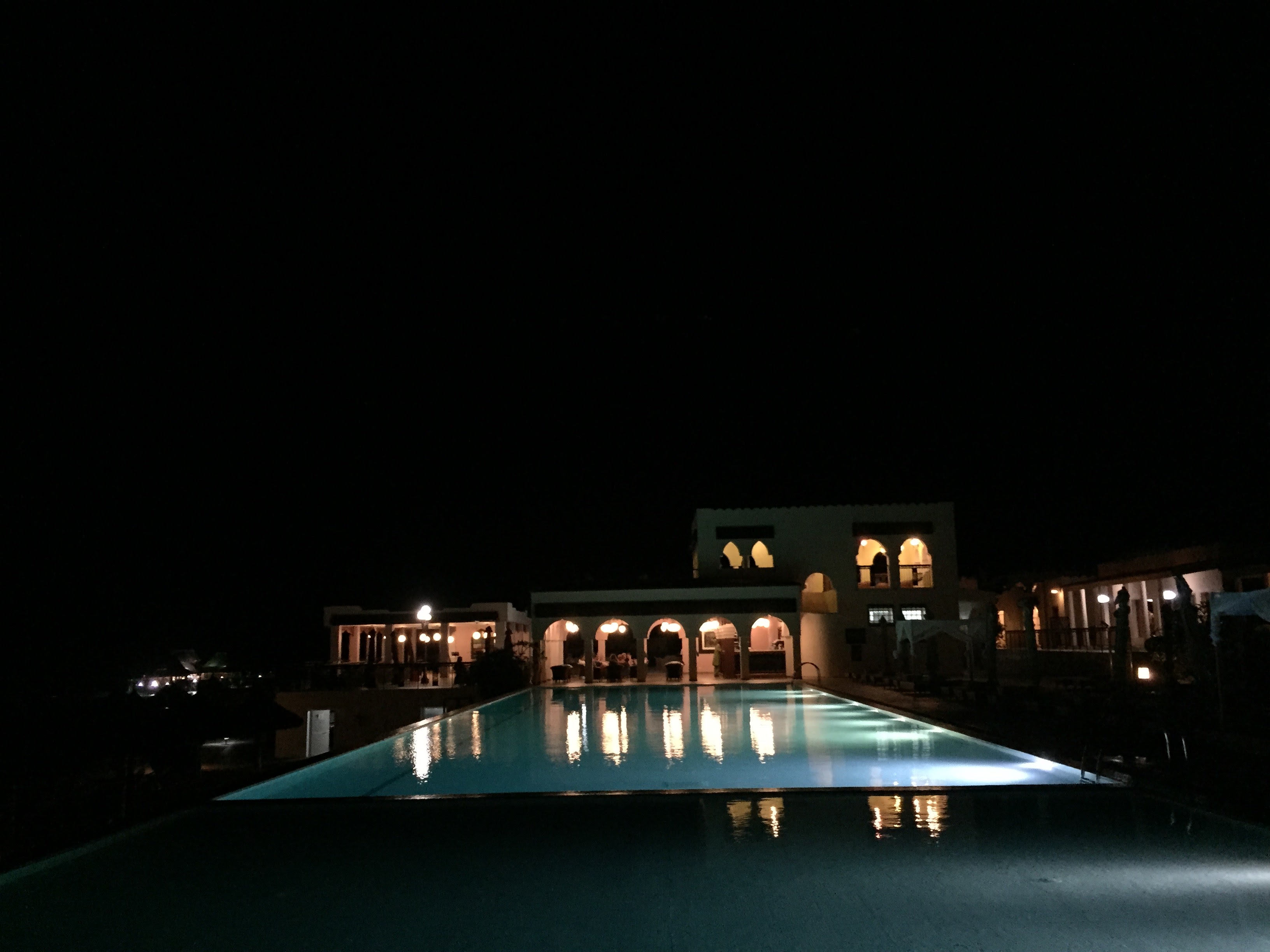 Hotel lit up at night, Moorish archways reflected in the illuminated pool
