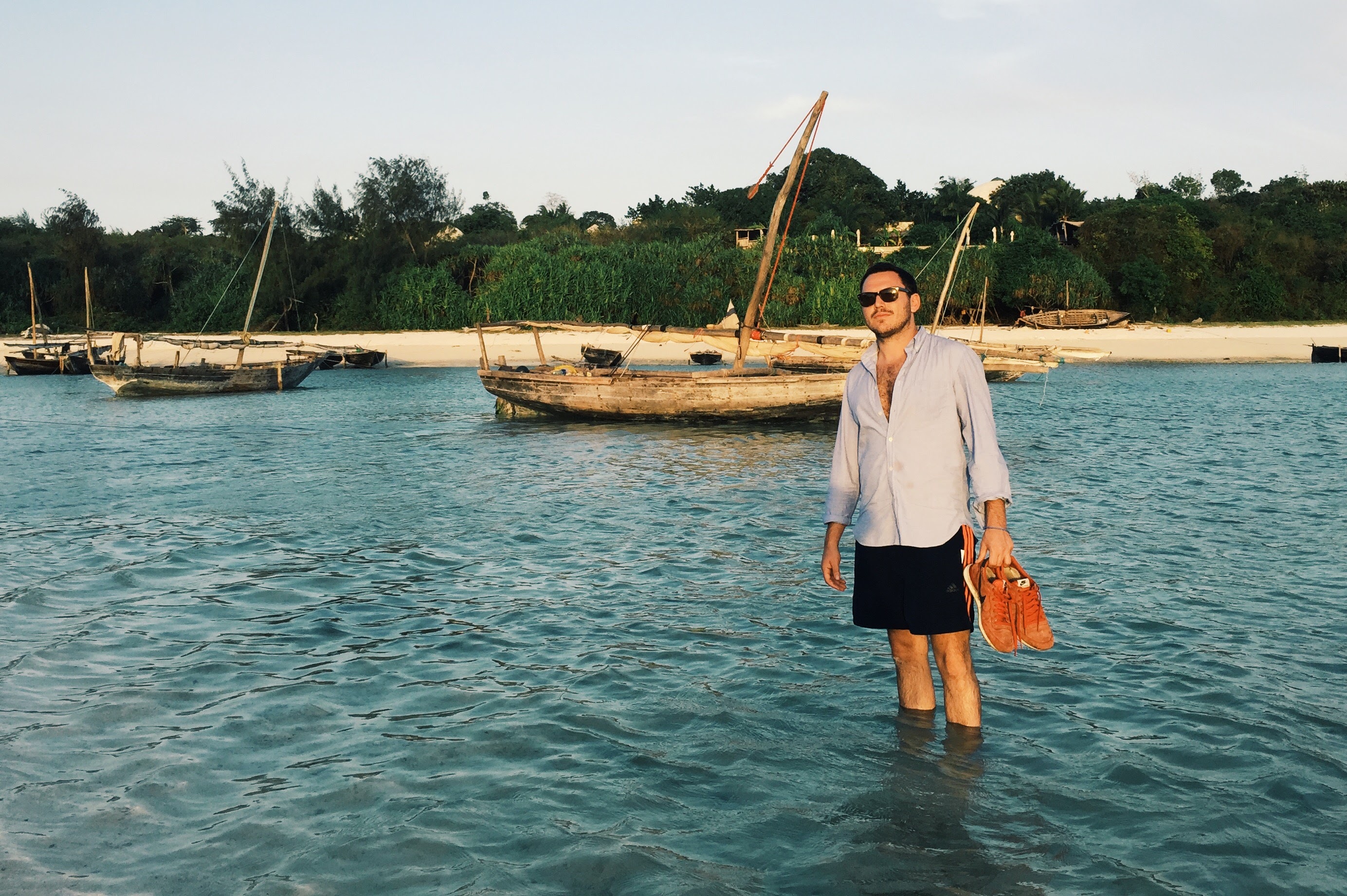 Standing in the warm shallows at Nungwi with traditional dhows moored behind